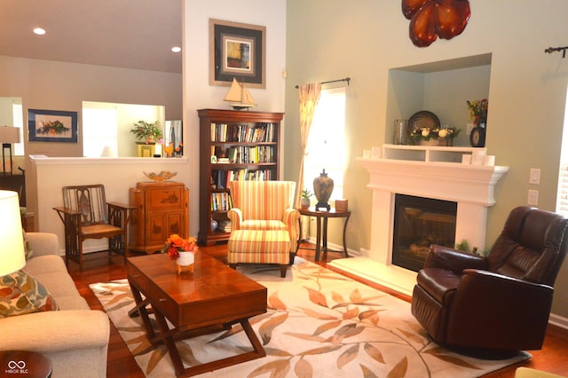 living area with a glass covered fireplace, wood finished floors, and recessed lighting