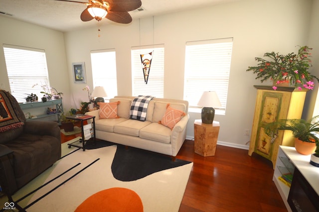 living area with plenty of natural light, visible vents, ceiling fan, and dark wood-style flooring