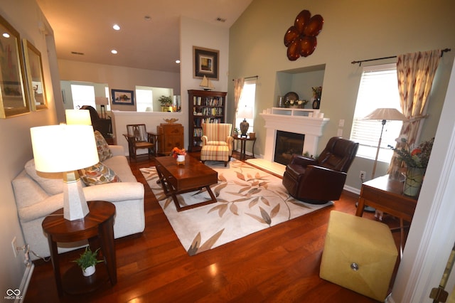 living room with baseboards, visible vents, a glass covered fireplace, wood finished floors, and recessed lighting