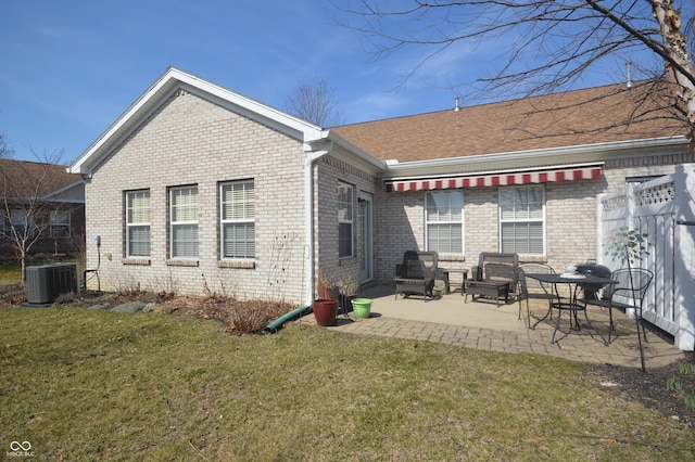 back of property with a lawn, a patio, fence, brick siding, and central AC unit