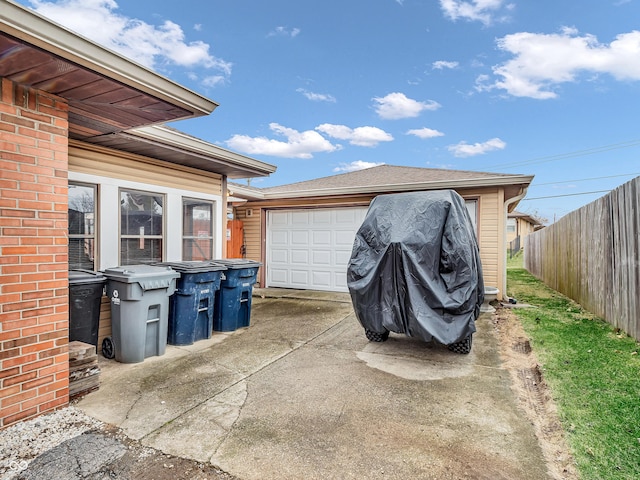 garage featuring driveway and fence