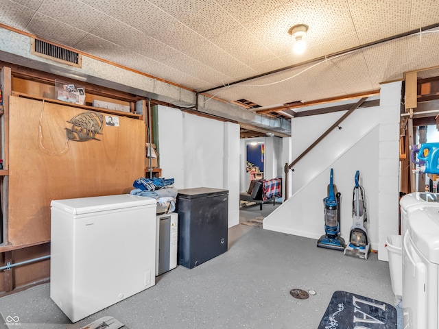 finished below grade area with washer and clothes dryer, fridge, and visible vents