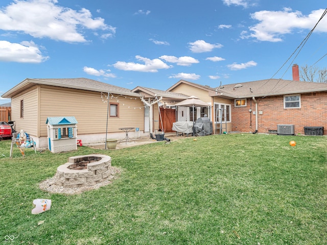 back of house with an outdoor fire pit, a lawn, fence, and a patio