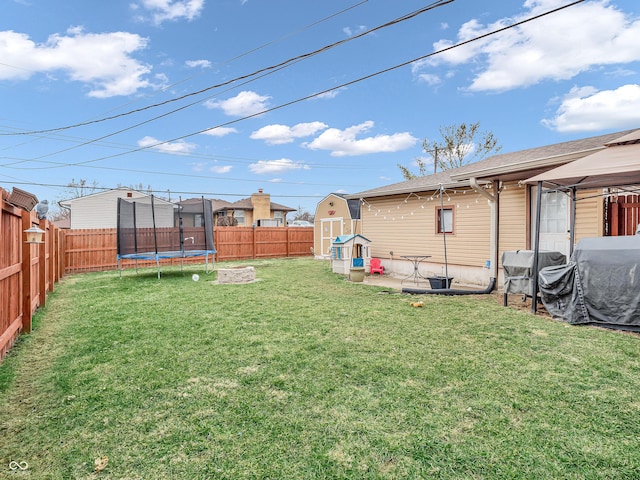 view of yard featuring a trampoline, a gazebo, a storage shed, a fenced backyard, and an outdoor structure