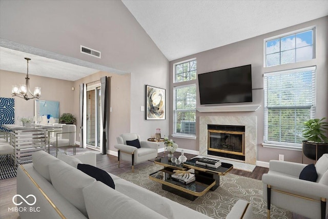 living area with high vaulted ceiling, wood finished floors, visible vents, and a high end fireplace