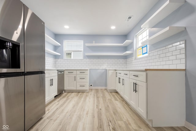 kitchen with open shelves, stainless steel fridge, white cabinetry, and decorative backsplash