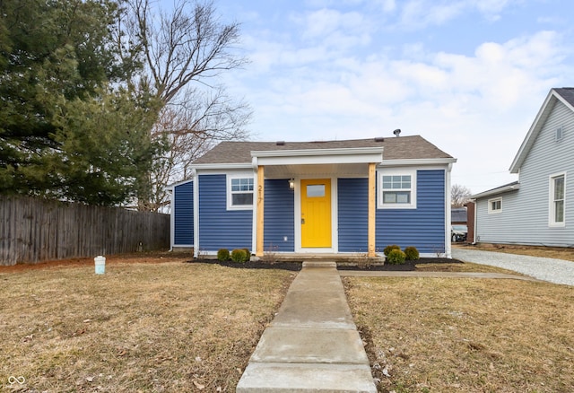 bungalow-style home with fence, a front lawn, and roof with shingles