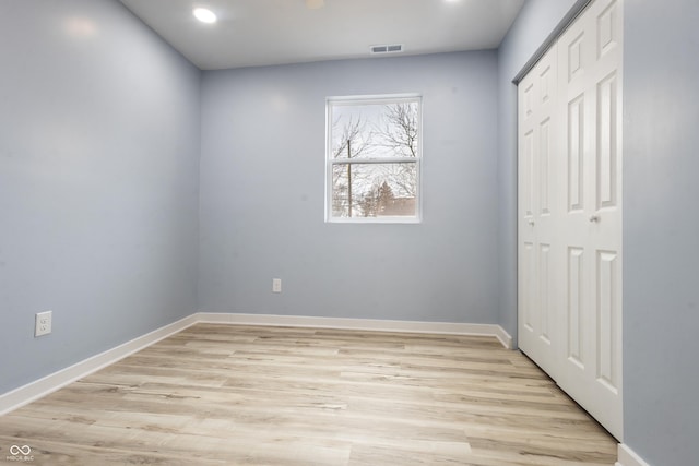 spare room featuring light wood-type flooring, visible vents, and baseboards