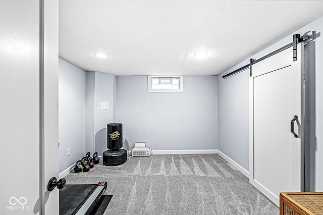 workout area featuring carpet floors, a barn door, and baseboards