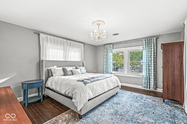 bedroom with a notable chandelier, baseboards, visible vents, and wood finished floors