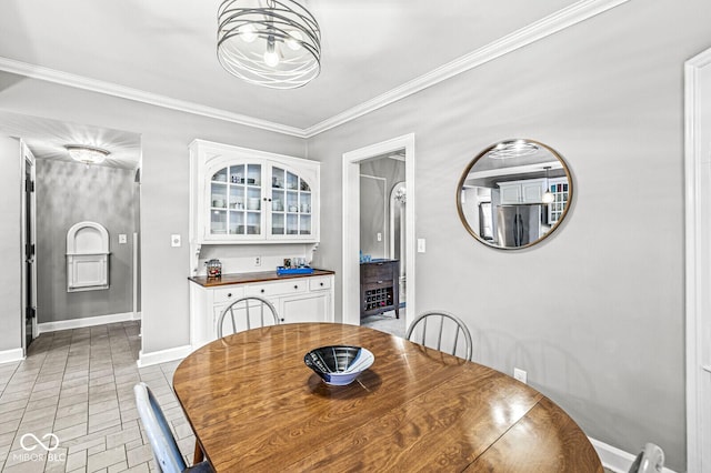 dining area featuring a notable chandelier, crown molding, baseboards, and light tile patterned floors