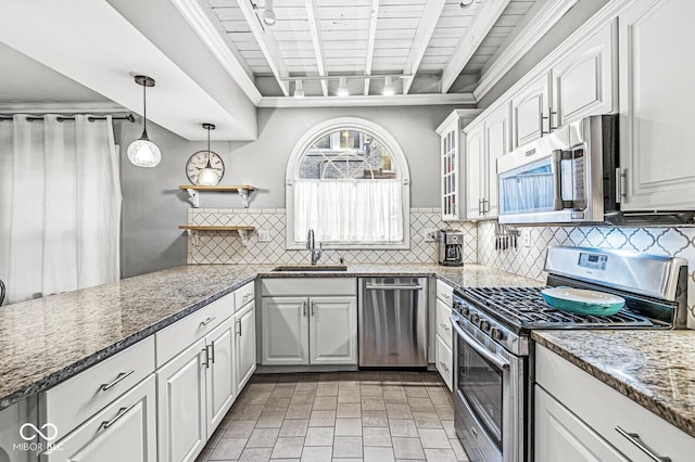 kitchen with stone counters, tasteful backsplash, appliances with stainless steel finishes, white cabinets, and a sink