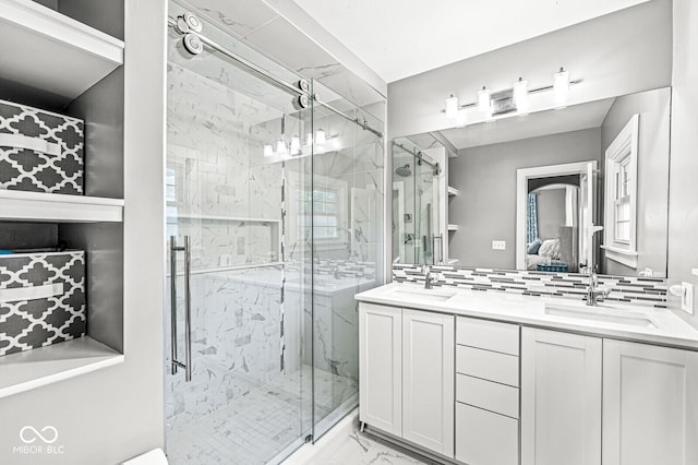 ensuite bathroom with marble finish floor, a sink, and a marble finish shower