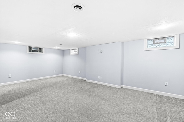 below grade area featuring carpet floors, baseboards, visible vents, and a textured ceiling