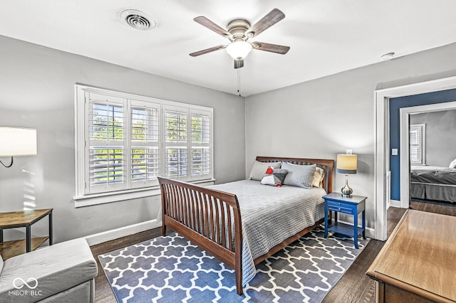 bedroom with a ceiling fan, wood finished floors, visible vents, and baseboards