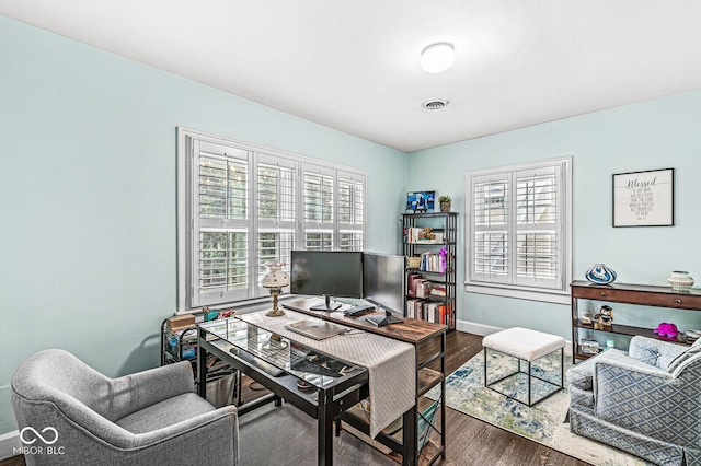 office area with wood finished floors, visible vents, and baseboards