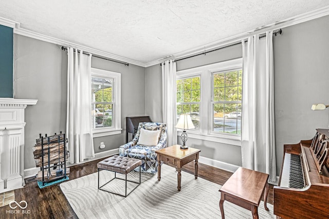 living area with a textured ceiling, ornamental molding, wood finished floors, and baseboards