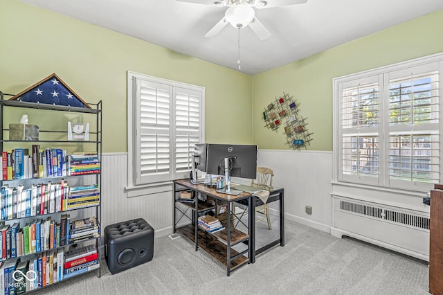 carpeted office featuring radiator, wainscoting, and ceiling fan