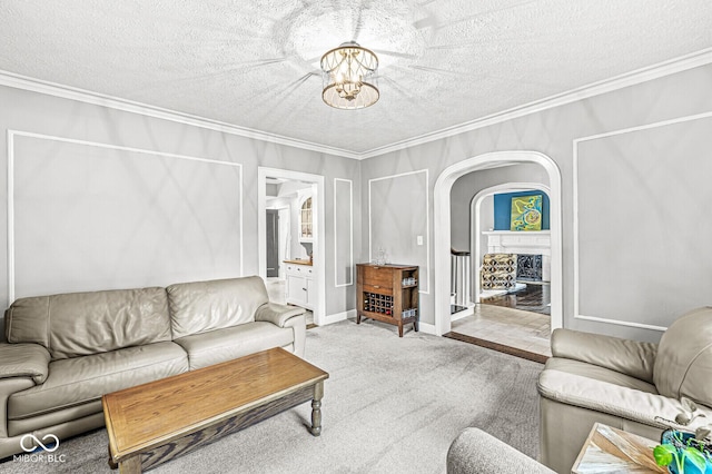 carpeted living area with crown molding, a fireplace, and a notable chandelier