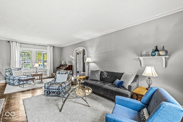 living room featuring ornamental molding, arched walkways, baseboards, and wood finished floors