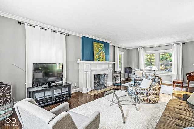 living room featuring a fireplace with flush hearth, crown molding, baseboards, and wood finished floors