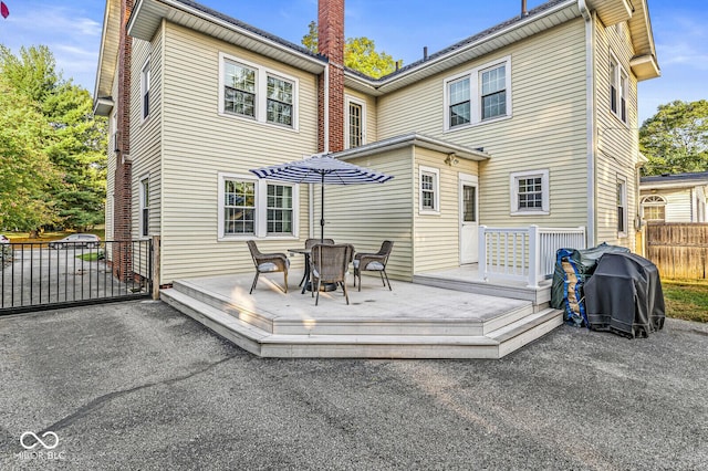 back of property featuring fence, a deck, and a patio