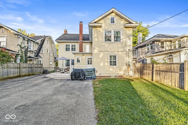 rear view of property featuring a fenced backyard, a chimney, and a lawn