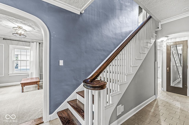 staircase featuring ornamental molding, arched walkways, a textured ceiling, and baseboards