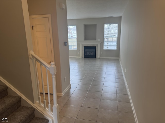 unfurnished living room featuring baseboards, a fireplace, stairs, and tile patterned floors