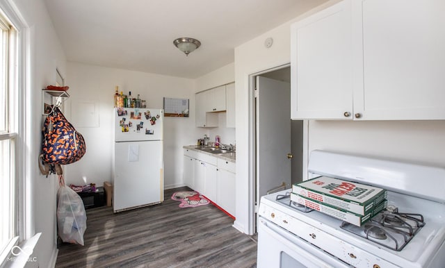 kitchen with dark wood-style flooring, light countertops, white cabinets, a sink, and white appliances