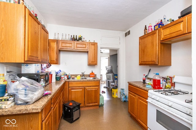 kitchen with a sink, visible vents, brown cabinetry, and gas range gas stove