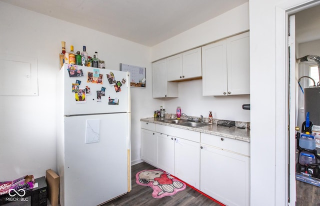 kitchen with dark wood-type flooring, freestanding refrigerator, light countertops, white cabinetry, and a sink