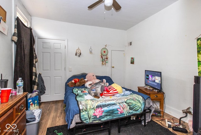 bedroom with a ceiling fan, visible vents, and wood finished floors