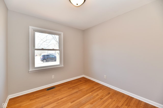 spare room featuring light wood-type flooring, visible vents, and baseboards