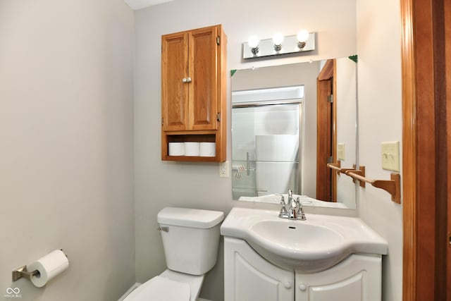 bathroom featuring vanity, a shower with door, and toilet