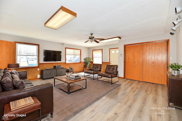 living room with light wood-style floors, baseboards, and a ceiling fan