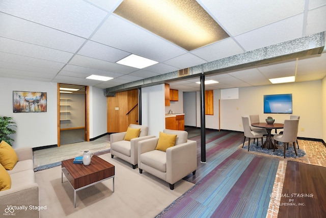 living room featuring a drop ceiling, wood finished floors, and baseboards