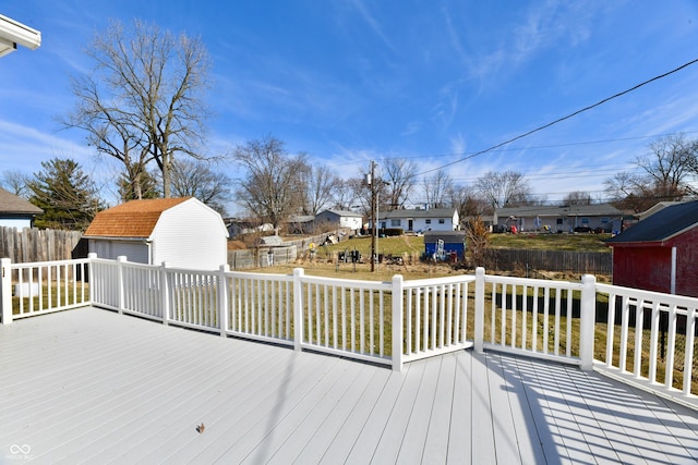 wooden deck featuring a storage shed, a residential view, fence, and an outbuilding