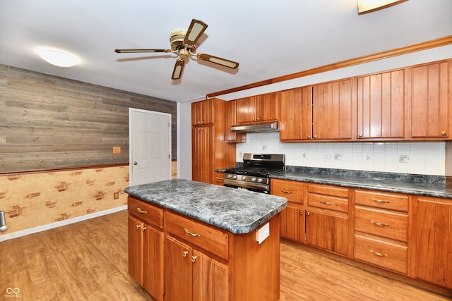 kitchen featuring light wood-style floors, stainless steel range with gas cooktop, brown cabinetry, and dark countertops