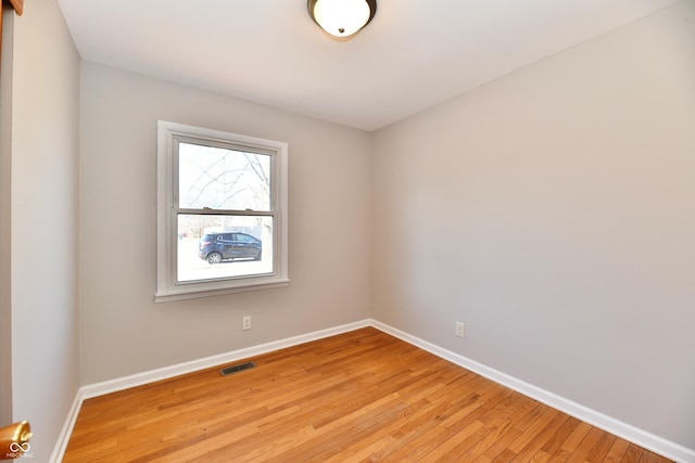 spare room featuring light wood-type flooring, visible vents, and baseboards