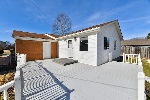 rear view of property featuring fence and a deck