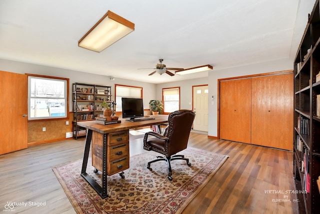 home office with light wood-type flooring, a ceiling fan, and baseboards