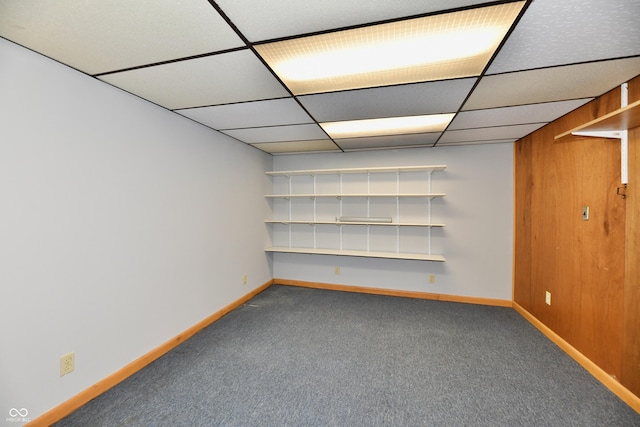 finished basement with carpet flooring, a paneled ceiling, and baseboards