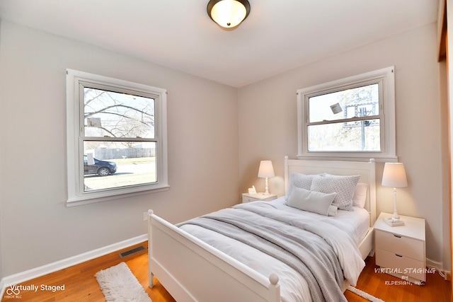 bedroom featuring baseboards, visible vents, and wood finished floors