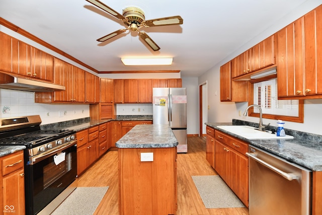 kitchen featuring under cabinet range hood, stainless steel appliances, a sink, a kitchen island, and dark countertops