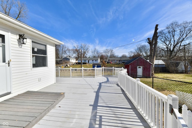 wooden deck featuring a residential view, a storage unit, fence, a yard, and an outdoor structure