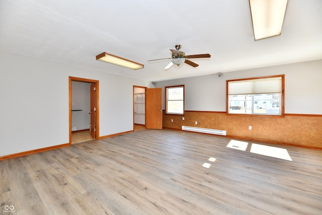 unfurnished room with a baseboard heating unit, wainscoting, ceiling fan, and wood finished floors