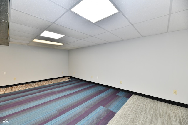 unfurnished room with a paneled ceiling, carpet, and baseboards