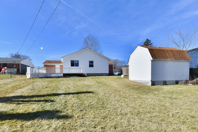 back of property featuring an outbuilding, a yard, a gambrel roof, a storage shed, and fence