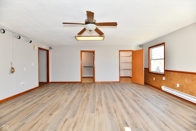 unfurnished room with light wood-type flooring, a wainscoted wall, ceiling fan, and baseboard heating